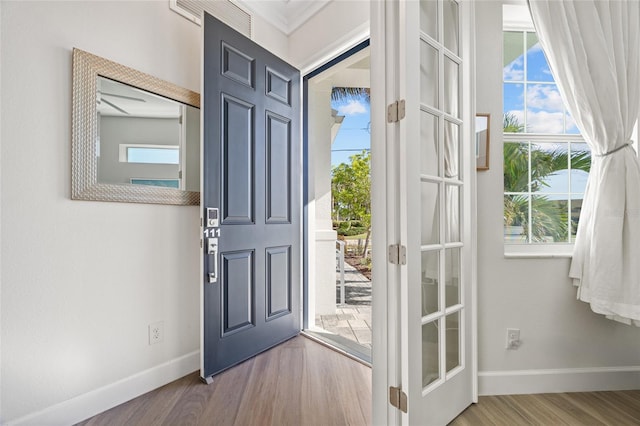 entryway featuring crown molding, plenty of natural light, hardwood / wood-style floors, and french doors