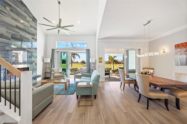 living room with hardwood / wood-style floors, ceiling fan, crown molding, and a high ceiling