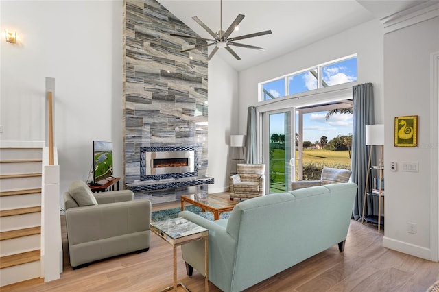 living room with a fireplace, hardwood / wood-style floors, high vaulted ceiling, and ceiling fan