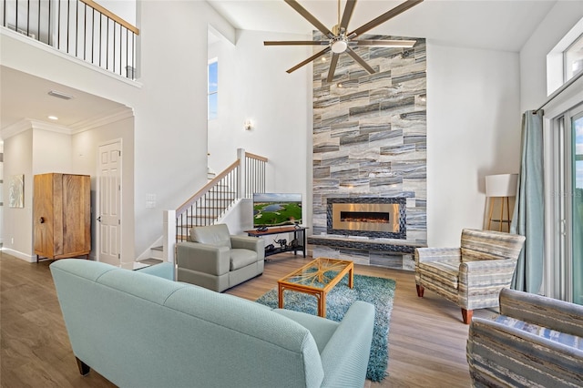 living room with a tiled fireplace, ceiling fan, high vaulted ceiling, and hardwood / wood-style flooring