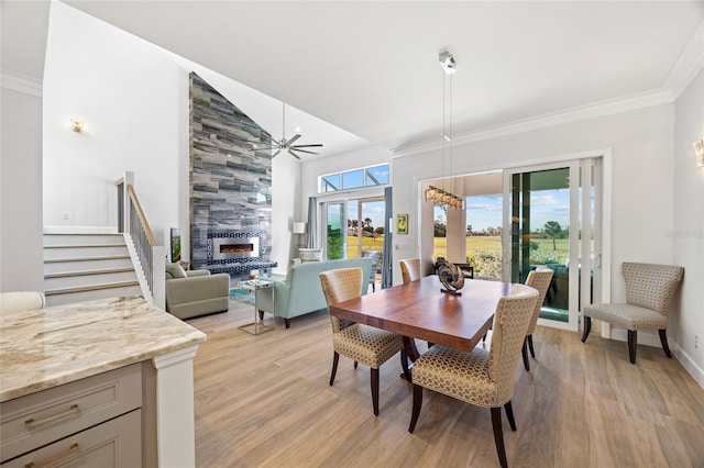 dining area featuring a tile fireplace, ceiling fan, crown molding, and light hardwood / wood-style floors