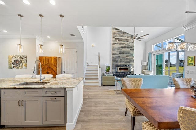 kitchen with light stone countertops, sink, decorative light fixtures, a fireplace, and gray cabinets