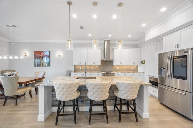 kitchen with white cabinetry, an island with sink, wall chimney exhaust hood, and stainless steel appliances