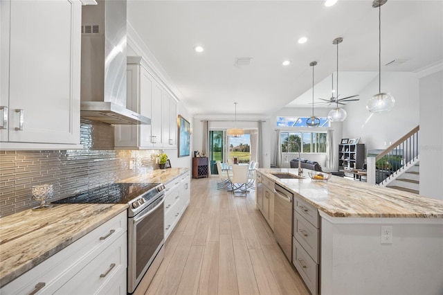 kitchen with pendant lighting, a spacious island, wall chimney exhaust hood, white cabinetry, and stainless steel appliances