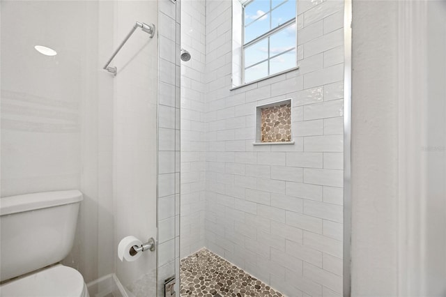 bathroom featuring toilet and a tile shower