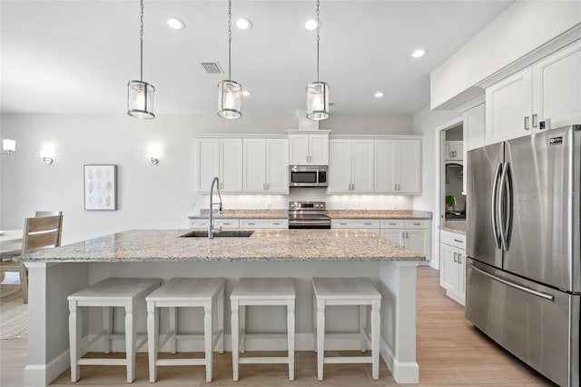 kitchen with a center island with sink, white cabinets, and stainless steel appliances