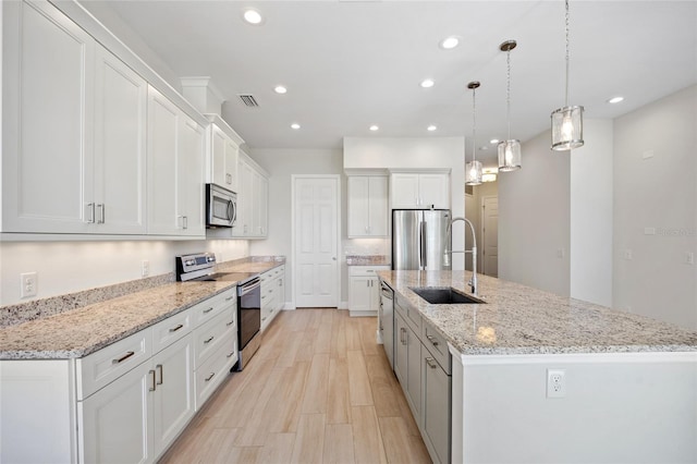 kitchen featuring white cabinets, decorative light fixtures, light hardwood / wood-style flooring, a large island, and stainless steel appliances