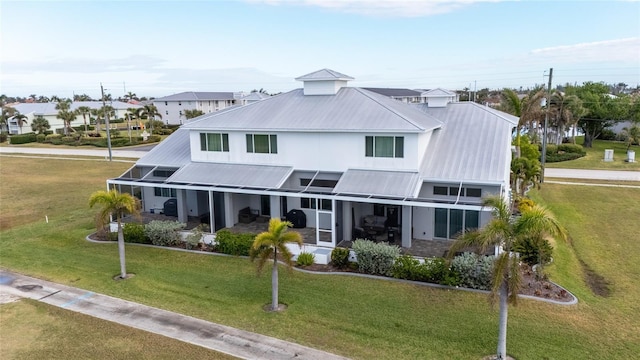 rear view of property with a lawn and a lanai