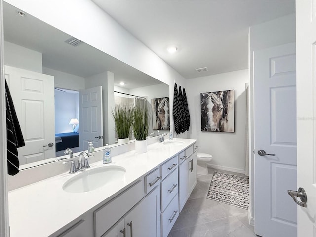 full bath featuring toilet, double vanity, visible vents, and a sink