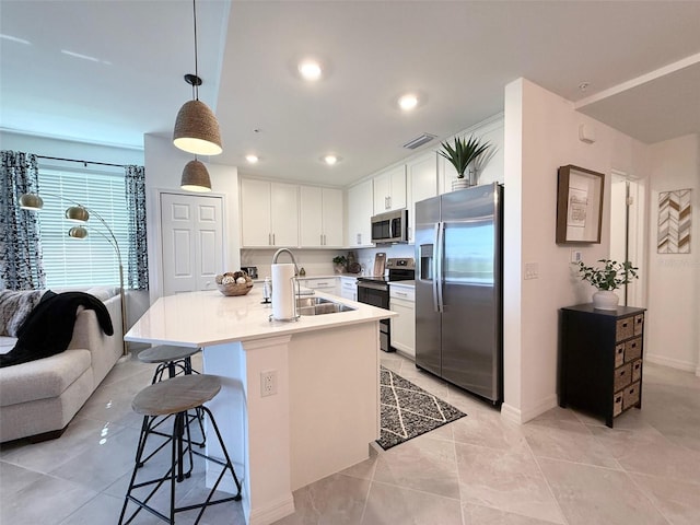 kitchen featuring a sink, white cabinetry, visible vents, a kitchen breakfast bar, and appliances with stainless steel finishes