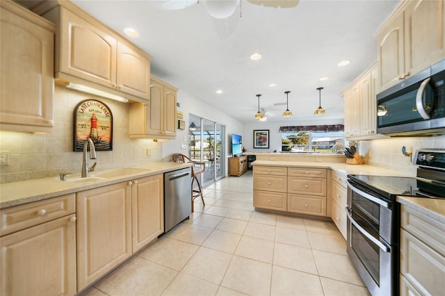 kitchen with sink, kitchen peninsula, pendant lighting, light brown cabinetry, and appliances with stainless steel finishes