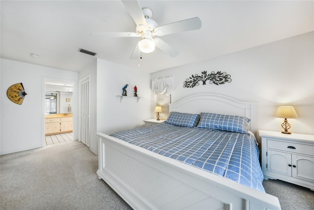 bedroom featuring ensuite bathroom, ceiling fan, and light colored carpet