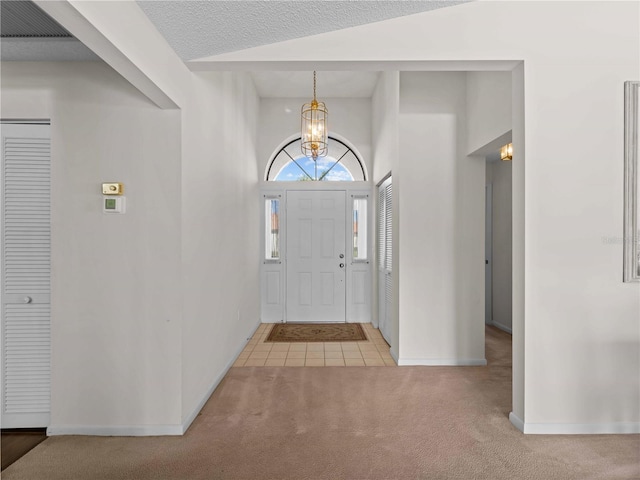 foyer featuring a textured ceiling, light carpet, and a chandelier