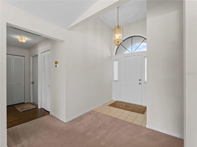 entrance foyer featuring a textured ceiling, a notable chandelier, and light carpet