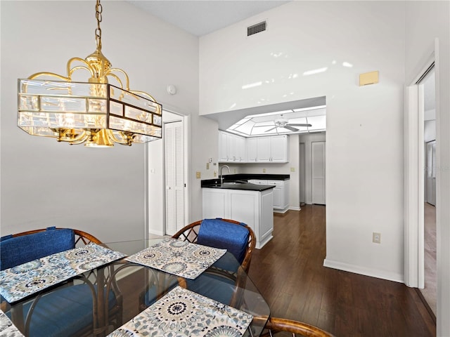 dining space featuring ceiling fan with notable chandelier, dark hardwood / wood-style flooring, and sink