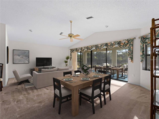 dining room featuring a textured ceiling, light colored carpet, vaulted ceiling, and ceiling fan