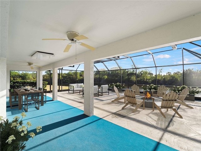 view of patio / terrace with a lanai, ceiling fan, and an outdoor living space with a fire pit