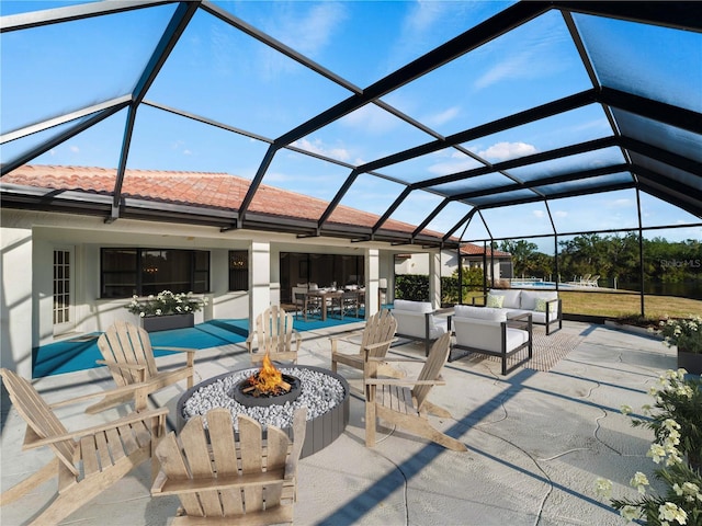 view of patio / terrace featuring glass enclosure and an outdoor living space with a fire pit