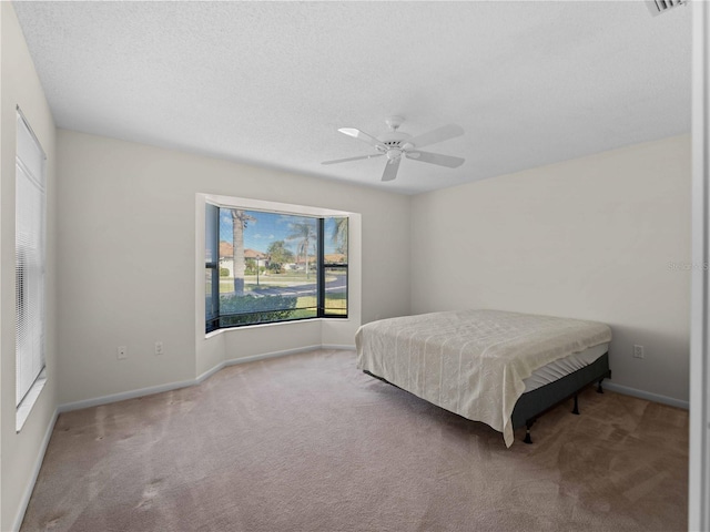 carpeted bedroom featuring ceiling fan and a textured ceiling