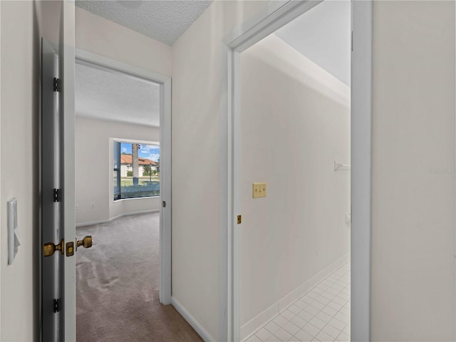 hall with light carpet and a textured ceiling