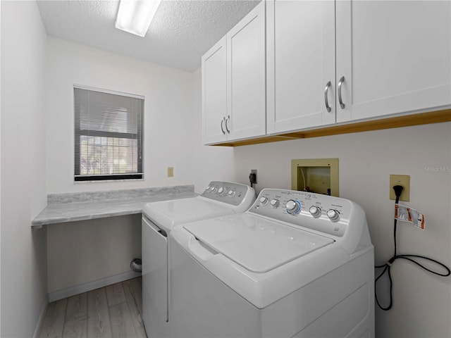 clothes washing area with light hardwood / wood-style floors, cabinets, a textured ceiling, and washing machine and clothes dryer