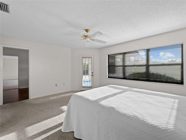 carpeted bedroom with ceiling fan and a textured ceiling