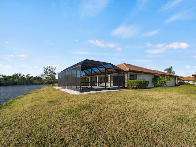 exterior space with a lawn, glass enclosure, a swimming pool, and a water view