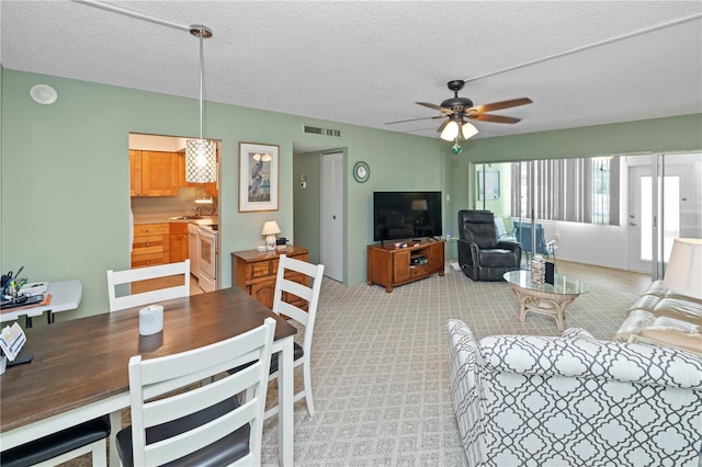 living room with ceiling fan, light colored carpet, and a textured ceiling