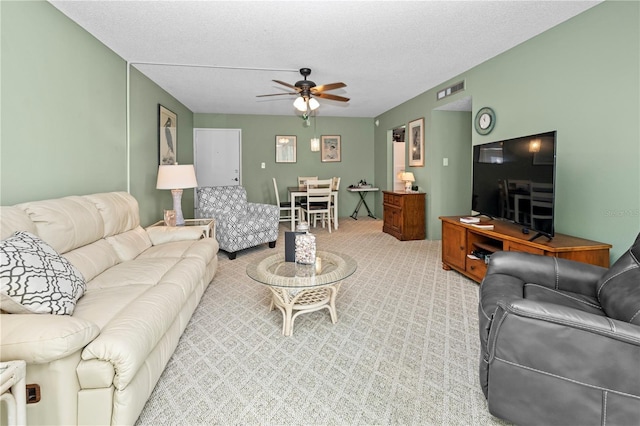 carpeted living room featuring ceiling fan and a textured ceiling