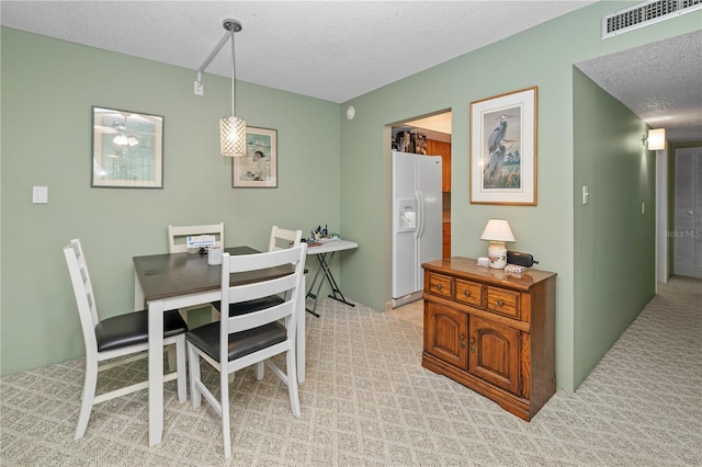 carpeted dining room featuring a textured ceiling