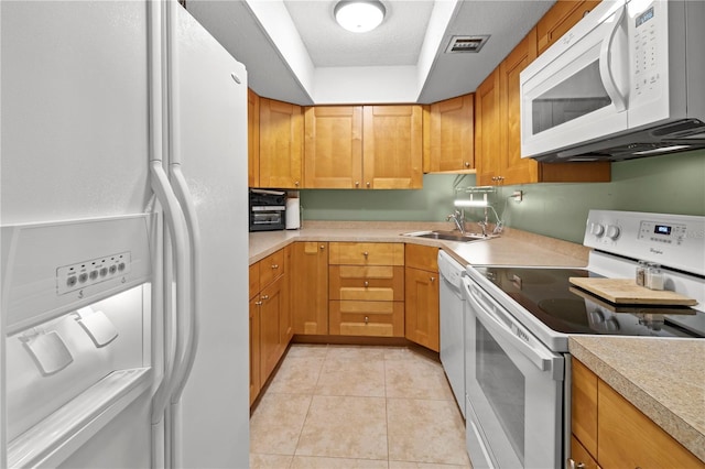 kitchen featuring a textured ceiling, light tile patterned flooring, white appliances, and sink