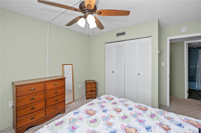 bedroom with ceiling fan, a closet, light carpet, and a textured ceiling