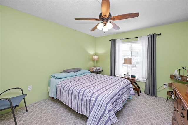 carpeted bedroom featuring ceiling fan and a textured ceiling