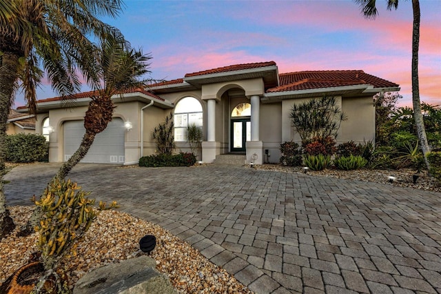 mediterranean / spanish-style home with a garage and french doors