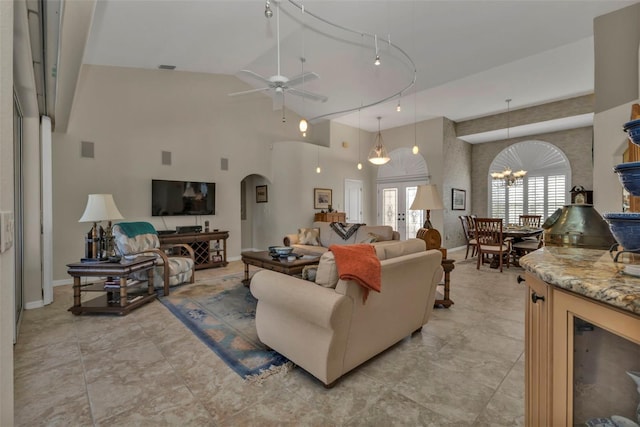 living room featuring ceiling fan with notable chandelier, rail lighting, and high vaulted ceiling