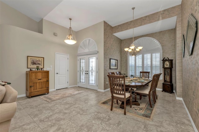 dining area featuring french doors, a towering ceiling, and a chandelier