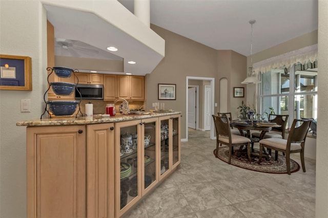 kitchen featuring light stone countertops, light brown cabinetry, backsplash, decorative light fixtures, and light tile patterned flooring