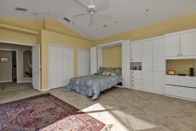 bedroom featuring ceiling fan, two closets, light tile patterned floors, and vaulted ceiling