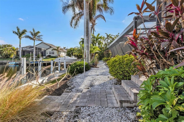 view of patio / terrace featuring glass enclosure, a water view, and a boat dock