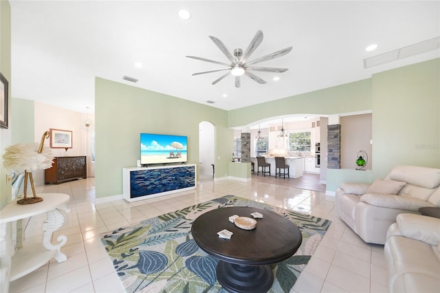 tiled living room with ceiling fan with notable chandelier