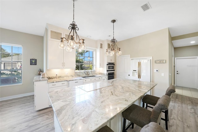 kitchen featuring white cabinetry, a kitchen island, light stone countertops, and white appliances