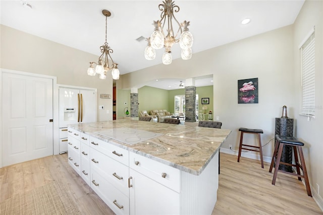 kitchen with white cabinetry, a center island, light stone counters, and light wood-type flooring