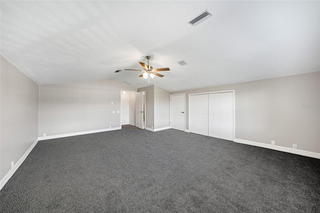 unfurnished bedroom featuring ceiling fan, a closet, dark carpet, and lofted ceiling