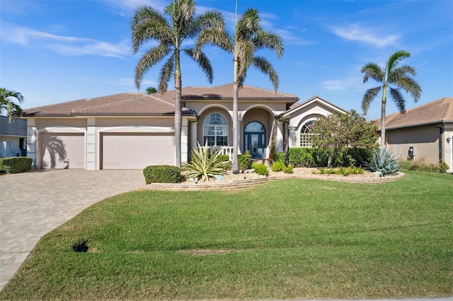 mediterranean / spanish home featuring a front yard and a garage