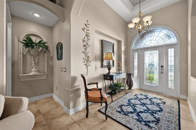 tiled entryway featuring a notable chandelier, crown molding, and a tray ceiling