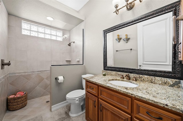 bathroom featuring toilet, vanity, and tiled shower