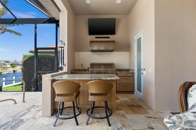 kitchen featuring a kitchen breakfast bar, tasteful backsplash, wall chimney exhaust hood, and sink