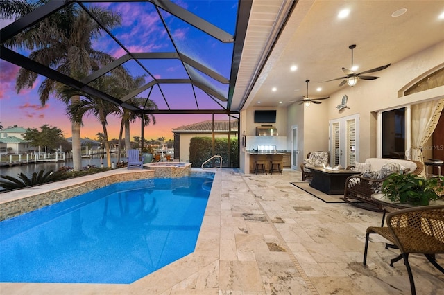 view of pool with an outdoor bar, ceiling fan, a lanai, a patio area, and exterior kitchen