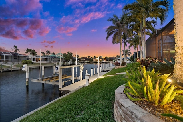 view of dock with a lawn and a water view