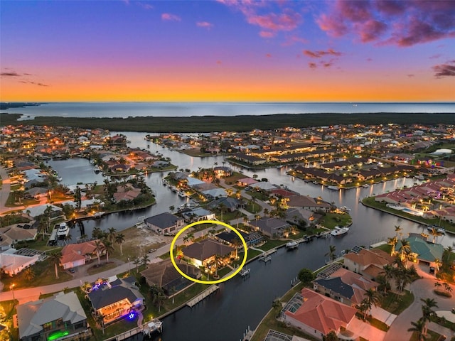 aerial view at dusk featuring a water view